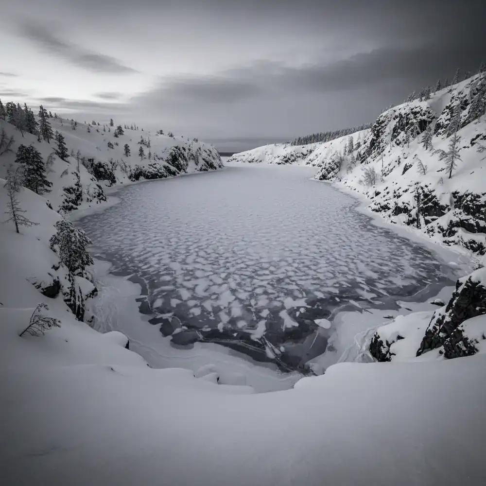 Sheltered frozen cove surrounded by snow-covered terrain